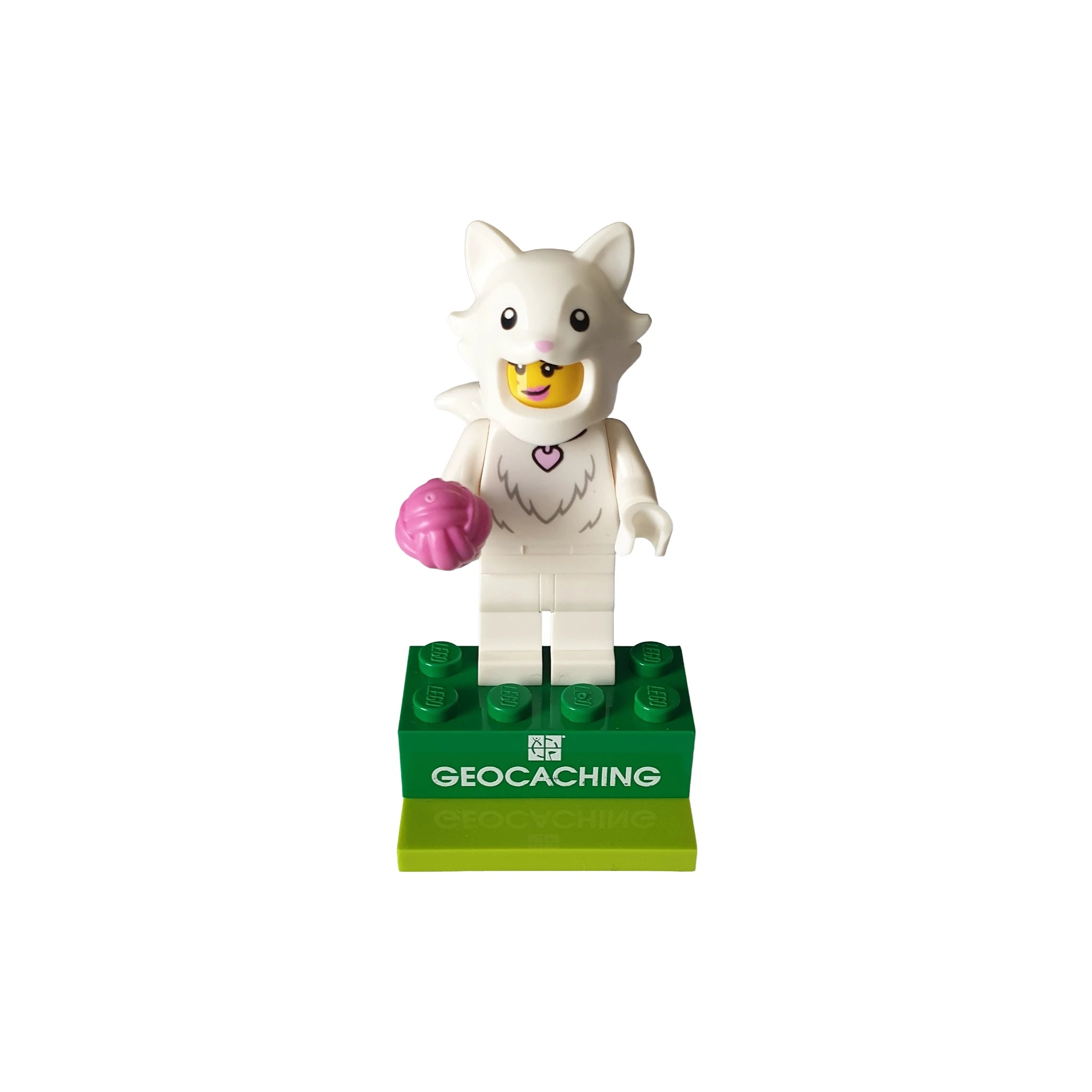 White cat costume LEGO minifigure holding pink accessory on green geocaching display base
