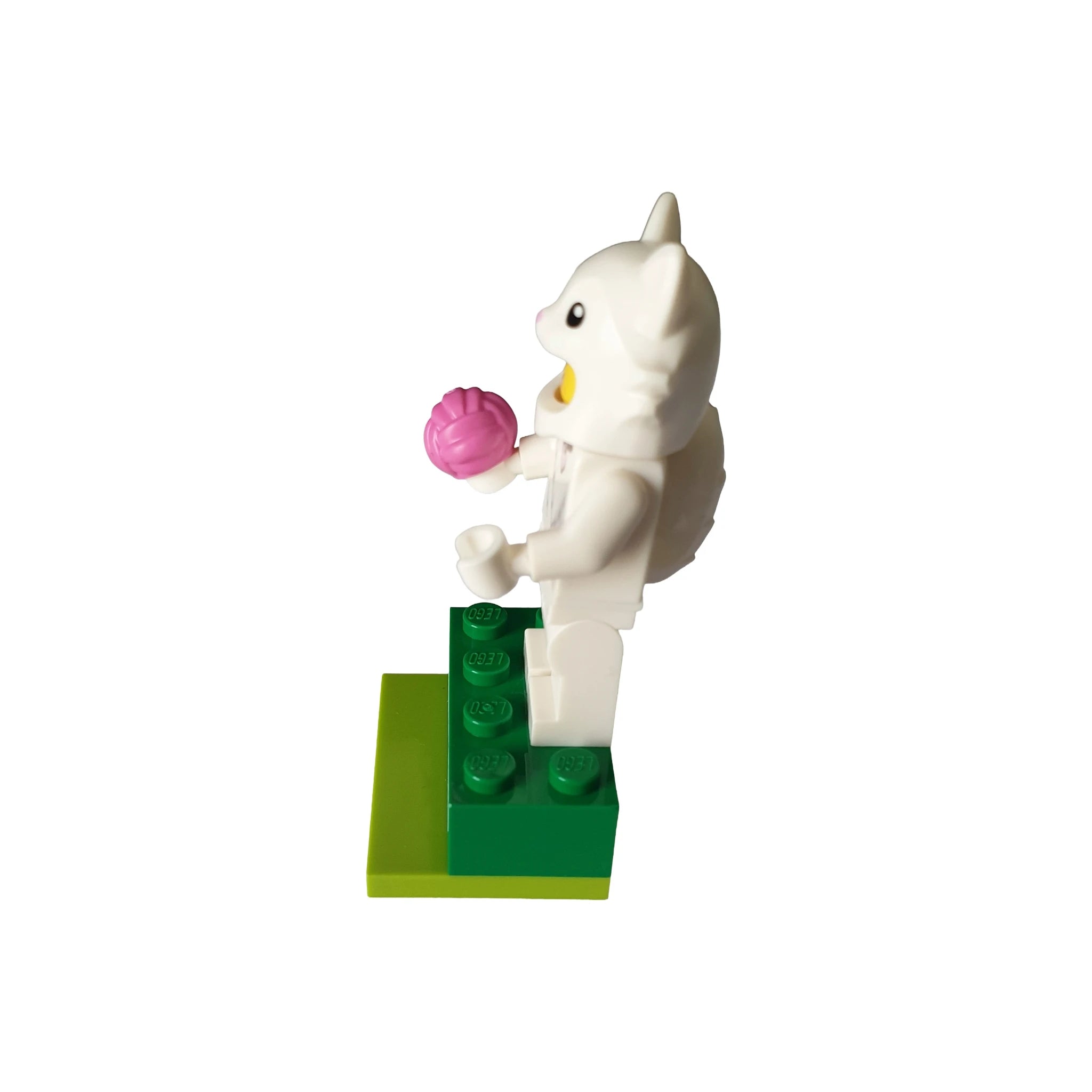 LEGO-style white cat costume figure holding pink flower on green base, geocaching container