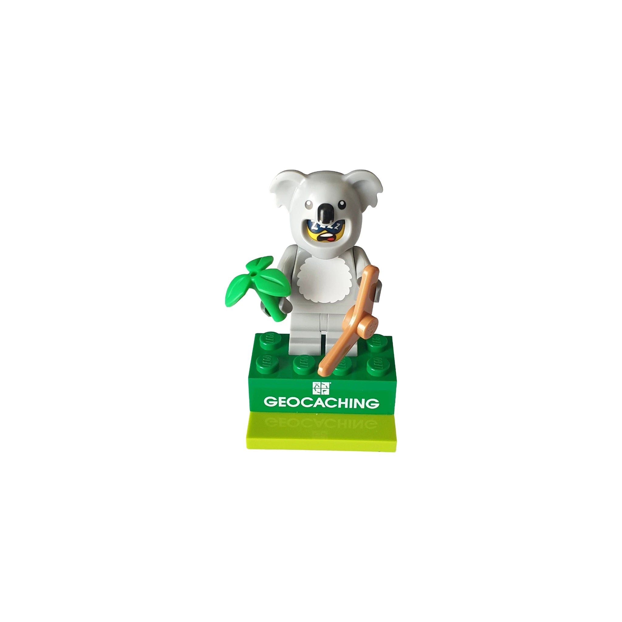 Koala mini figure holding a branch with leaves on a green geocaching base