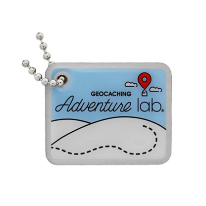 Adventure Lab travel tag with blue sky, red location pin, winding dotted trail and silver ball chain on a white background