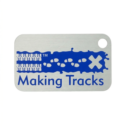 Blue Making Tracks metal trackable tag with tyre tracks, footprints and X design on a white background