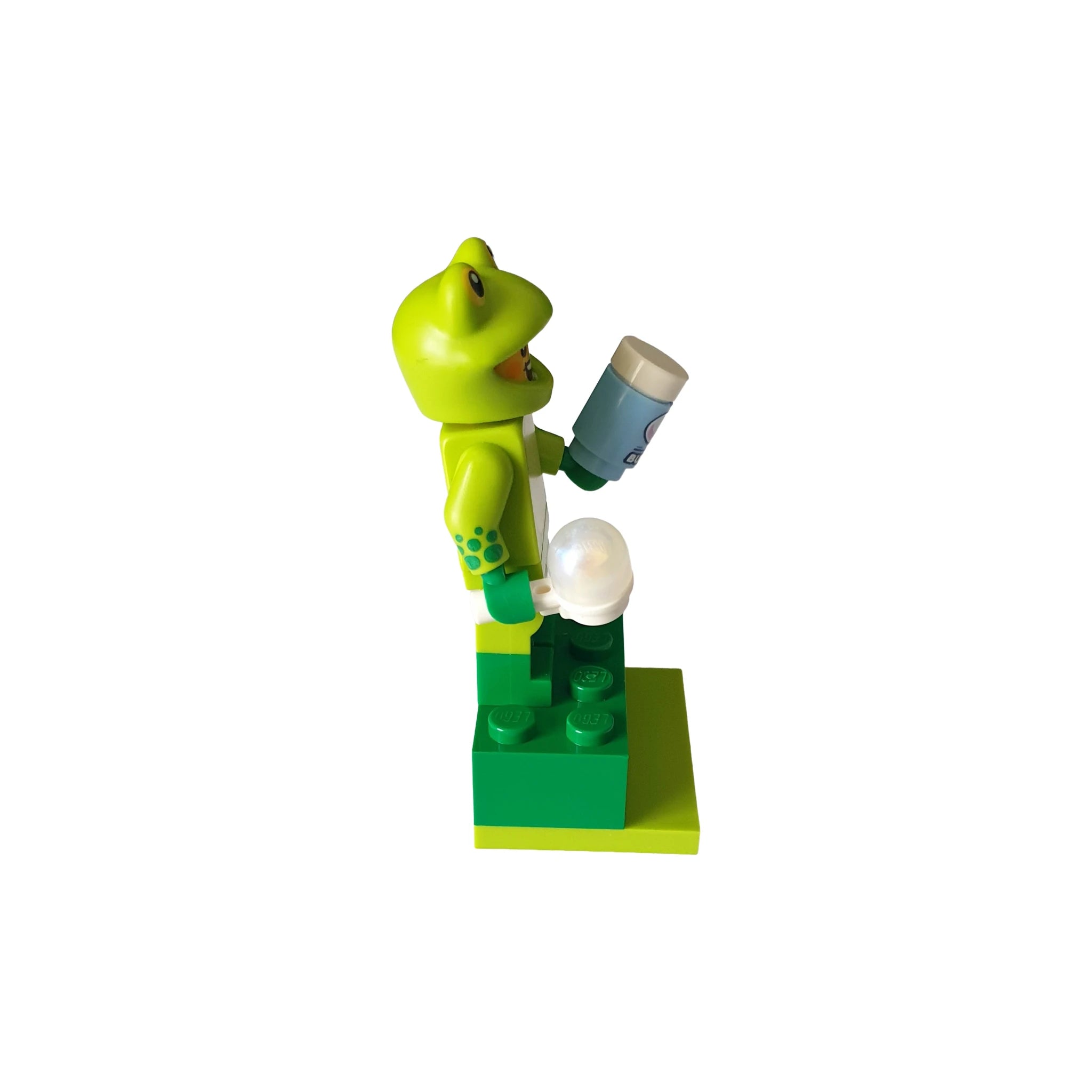 Lego minifigure in frog costume holding a cup, standing on a green base for geocaching