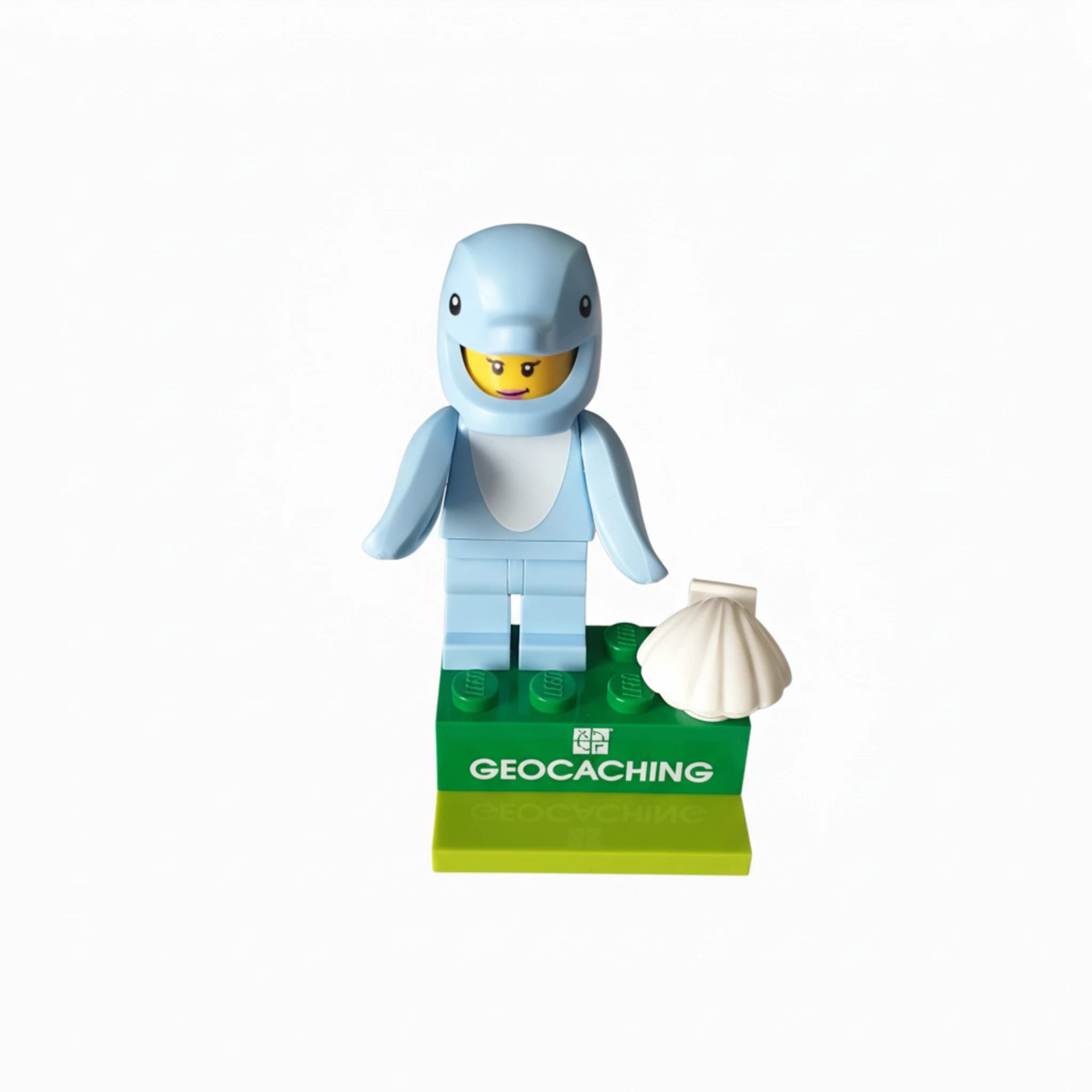Geocaching dolphin minifigure toy with shell accessory on green display base