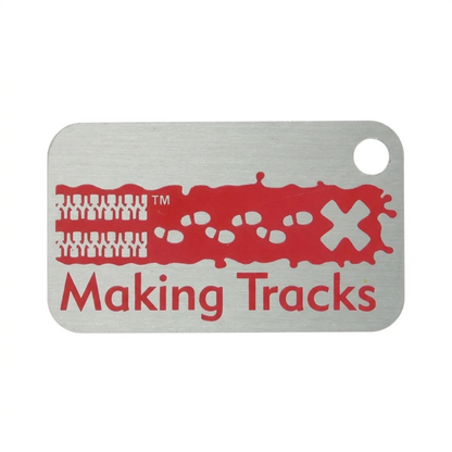 Red Making Tracks metal trackable tag with tyre tracks, footprints and X design on a white background