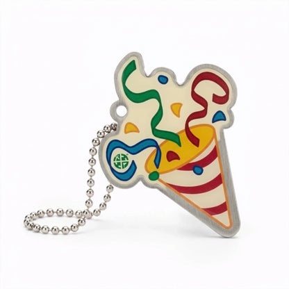 Community Block Party Trackable with a red-striped party popper, colourful streamers and confetti, and silver ball chain on white